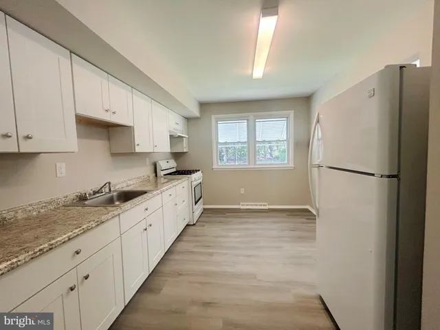 a large kitchen with a refrigerator a sink a stove and white cabinets