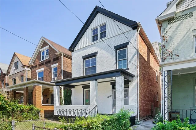 a view of a white house next to a yard