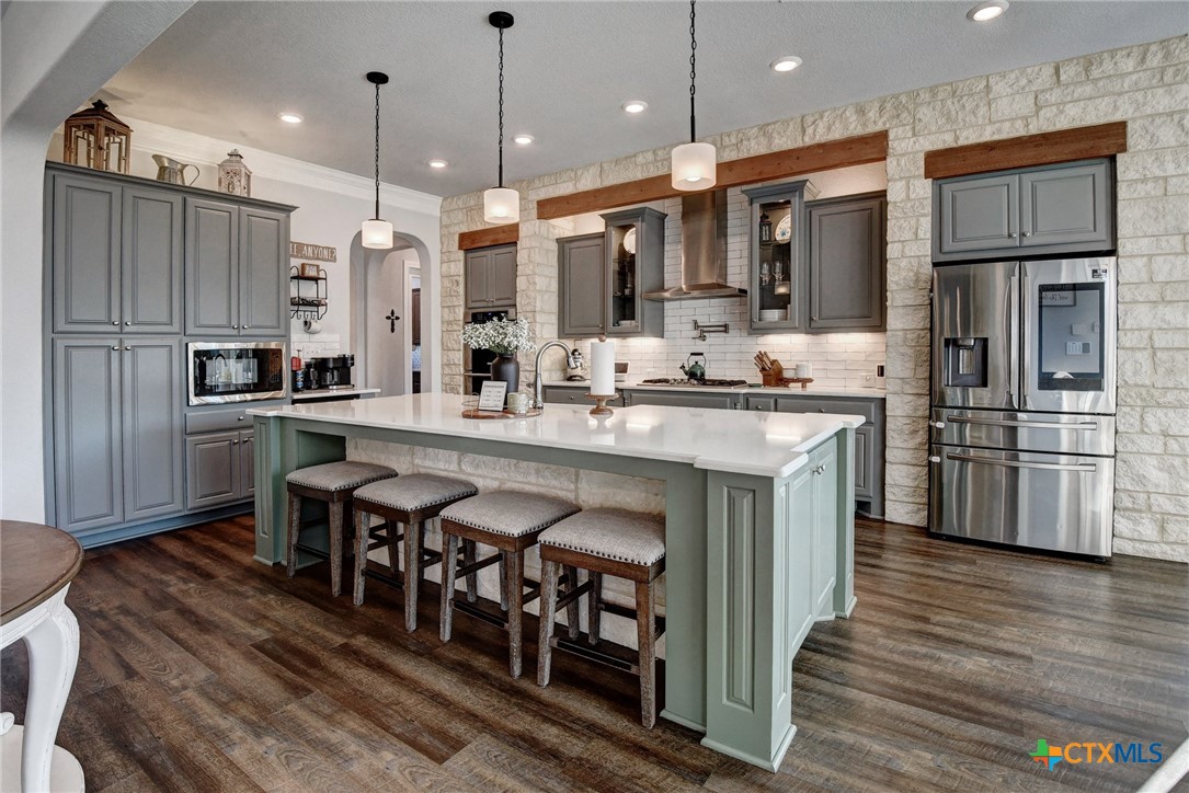 222 August Avenue Shiner, TX 77984 - Photo 13 of 48 a kitchen with stainless steel appliances kitchen island granite countertop a table chairs sink refrigerator and microwave
