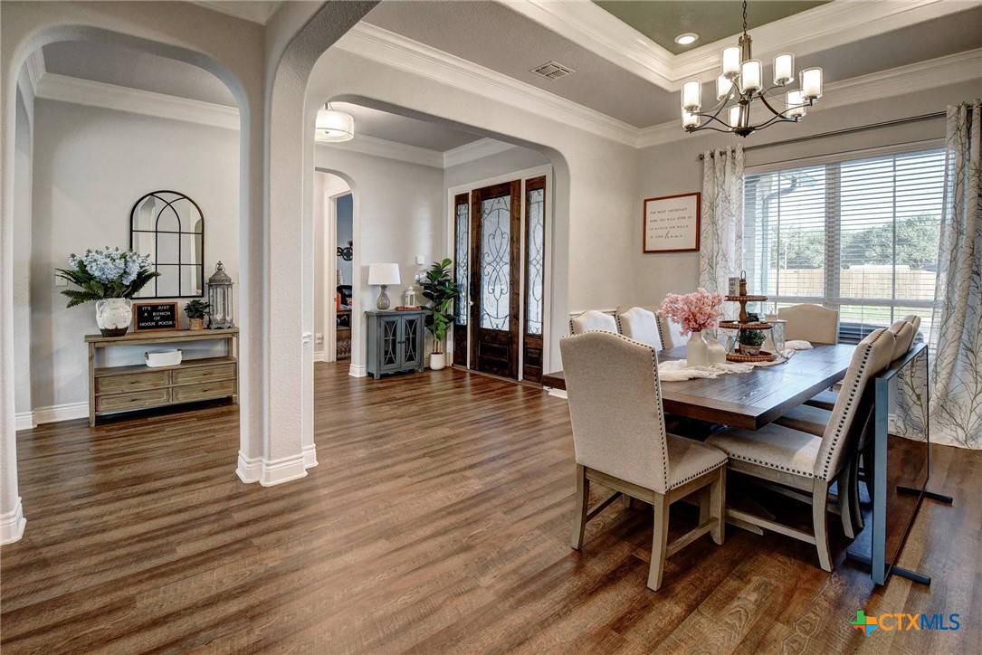 222 August Avenue Shiner, TX 77984 - Photo 7 of 48 a dining room with wooden floor a chandelier a wooden table and chairs