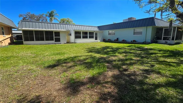 a view of a brick house with a small yard plants and palm trees