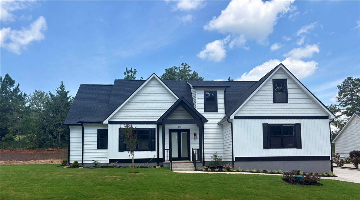 854 Perkins Creek Road Seneca, SC 29678 - Photo 1 of 34 Crisp gables and dark trim define this classic farmhouse facade over a manicured green lawn.