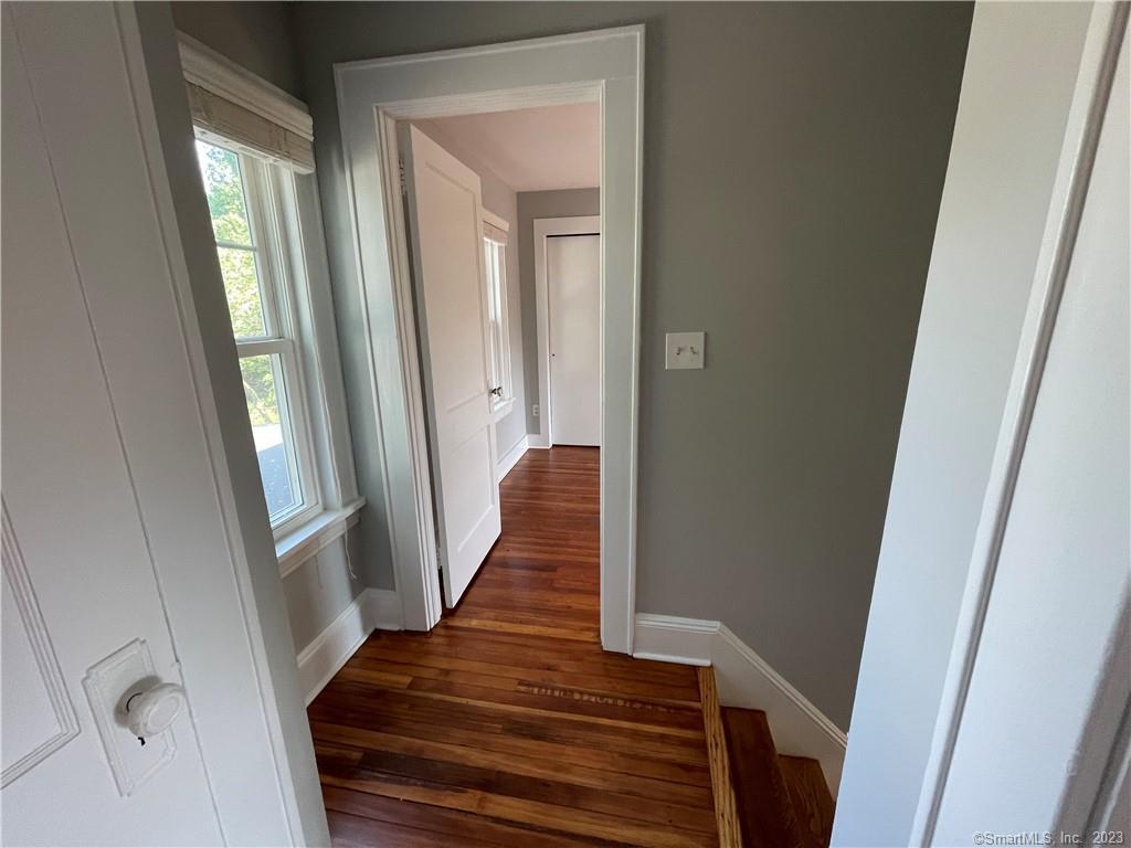 218 Ruane Street Fairfield, CT 06824 - Photo 17 of 26 a view of a hallway with wooden floor and staircase