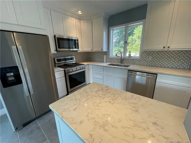 a kitchen with a sink a microwave a refrigerator and cabinets