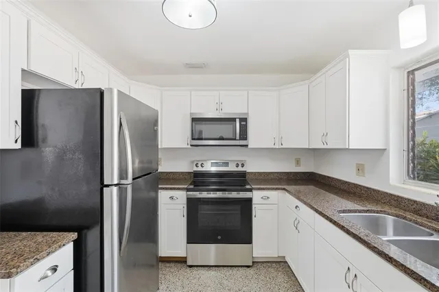 a kitchen with granite countertop white cabinets white stainless steel appliances and a sink