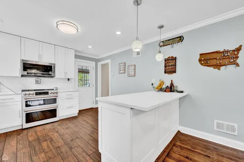 a kitchen with stainless steel appliances a stove a microwave and white cabinets