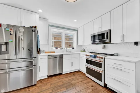 a kitchen with cabinets stainless steel appliances and wooden floor