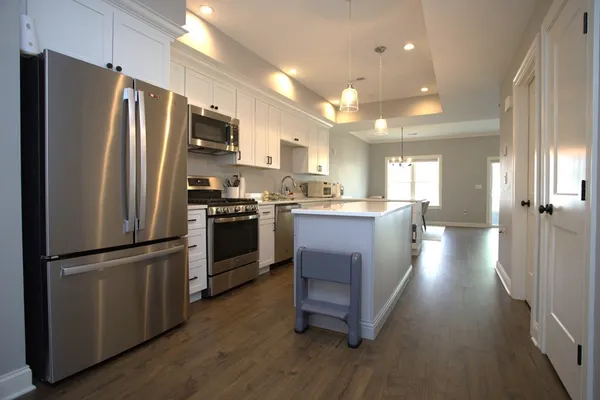 a kitchen with stainless steel appliances a refrigerator a stove a sink dishwasher a oven with white cabinets and wooden floor