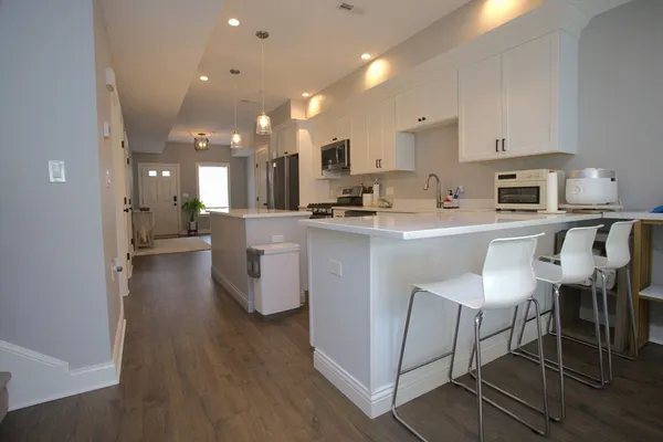 a kitchen with stainless steel appliances granite countertop a table chairs microwave and sink