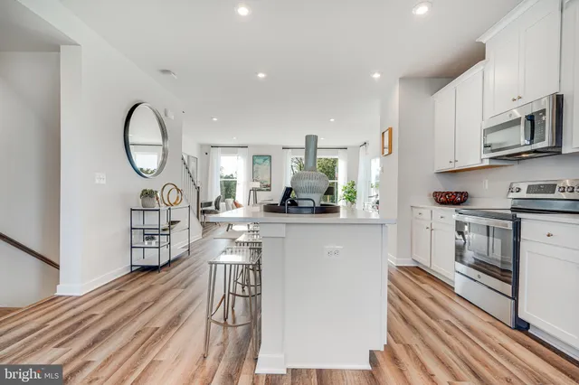 a kitchen with stainless steel appliances granite countertop a stove a sink dishwasher and a microwave with wooden floor