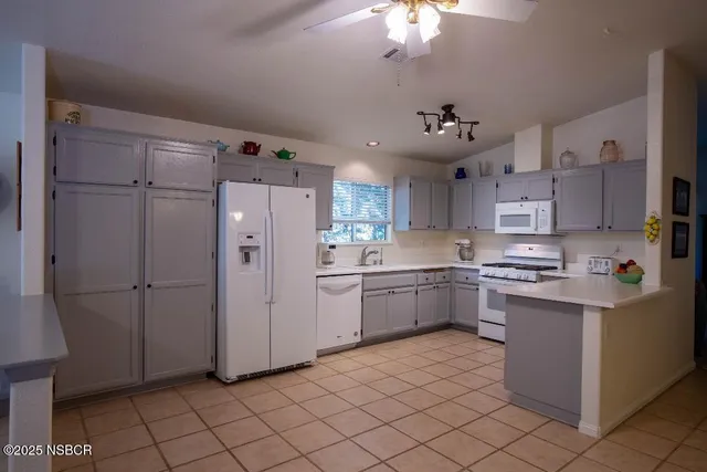 a kitchen with stainless steel appliances granite countertop a refrigerator a sink dishwasher a stove and a dining table with wooden floor