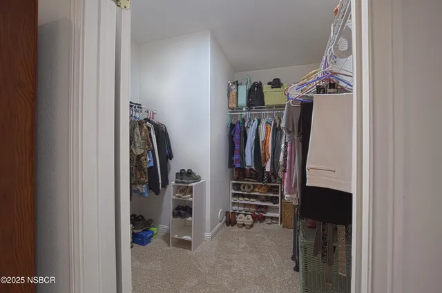 a view of walk in closet with clothes