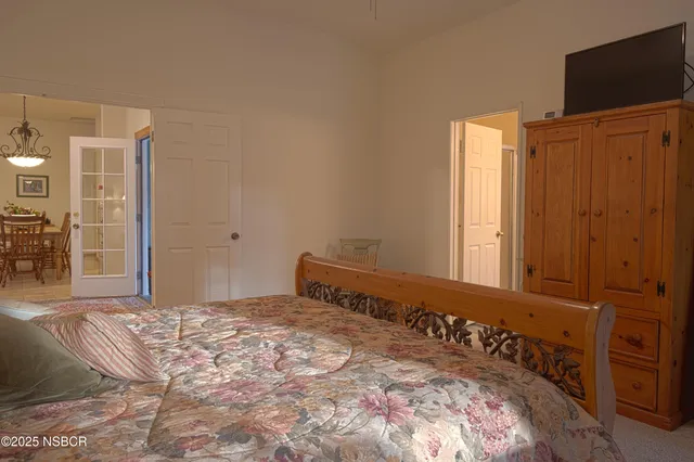 a bedroom with a bed and a flat tv screen on dresser