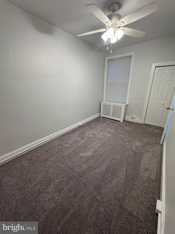 an empty room with a ceiling fan and carpet