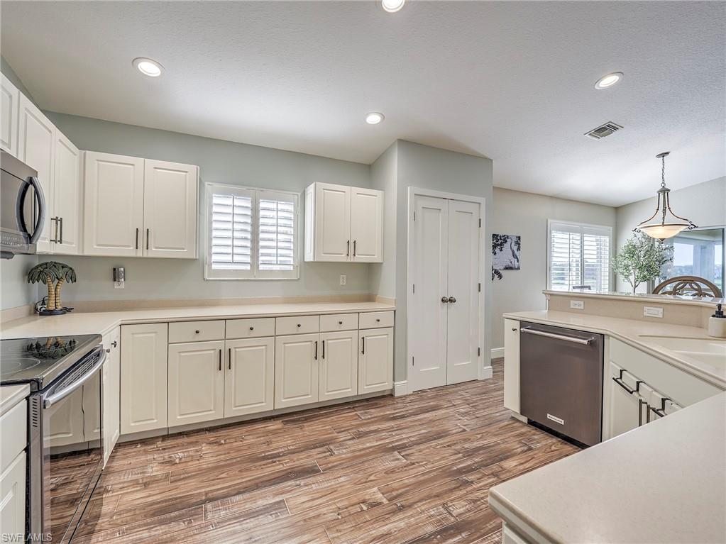 8460 Southbridge Drive, Unit 2 Estero, FL 33967 - Photo 18 of 42 a large kitchen with granite countertop a stove top oven a sink a window and white cabinets