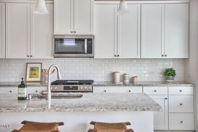a kitchen with granite countertop a stove a sink and a white cabinets