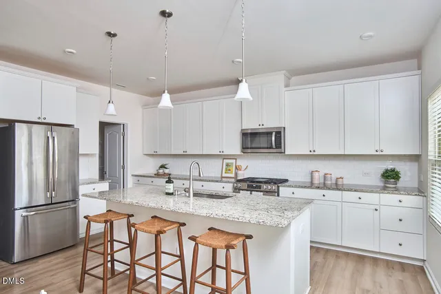 a kitchen with stainless steel appliances granite countertop a sink a stove a refrigerator a center island and cabinets