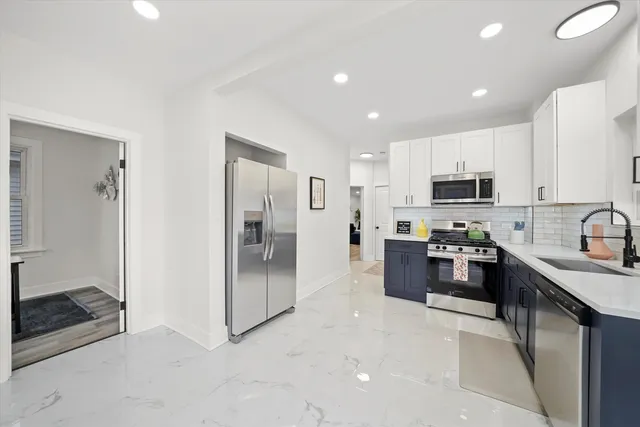 a kitchen with stainless steel appliances granite countertop a refrigerator a sink a stove top oven and a refrigerator