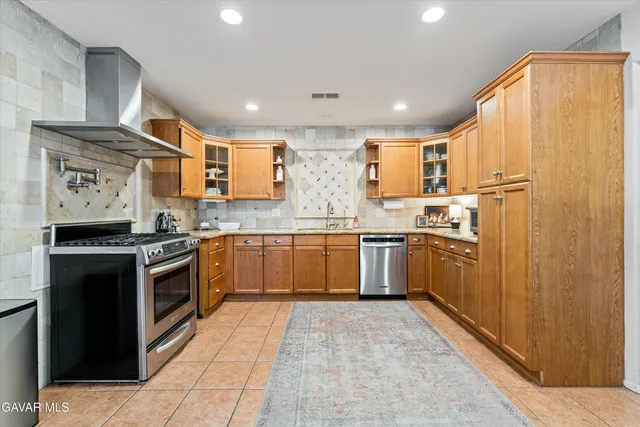 a kitchen with stainless steel appliances granite countertop a stove a sink dishwasher and a refrigerator