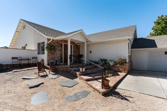 a view of a patio with a table and chairs under an umbrella