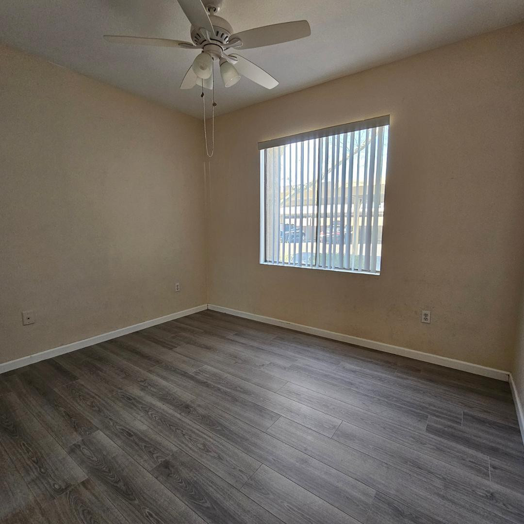 18416 North Cave Creek Road, Unit 2057 Phoenix, AZ 85032 - Photo 9 of 11 an empty room with wooden floor fan and windows
