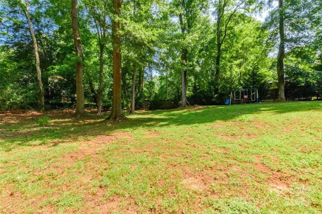 a view of backyard of house with wooden deck and large trees