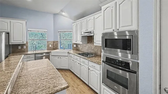 a kitchen with stainless steel appliances granite countertop a stove a sink and a microwave