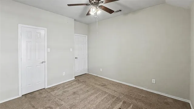 an empty room with a ceiling fan and a window