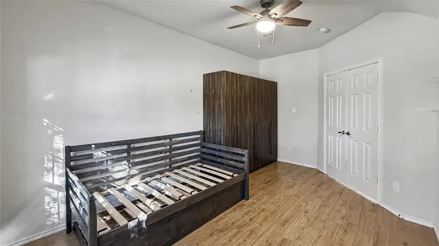 a view of an empty room with wooden floor and a ceiling fan