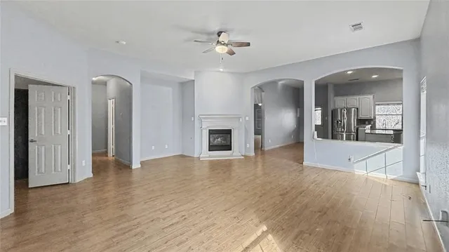 an empty room with wooden floor and a kitchen