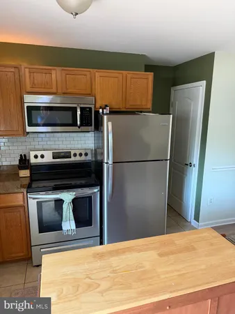 a kitchen with granite countertop a refrigerator and a stove top oven