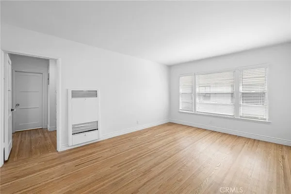 an empty room with wooden floor cabinet and windows