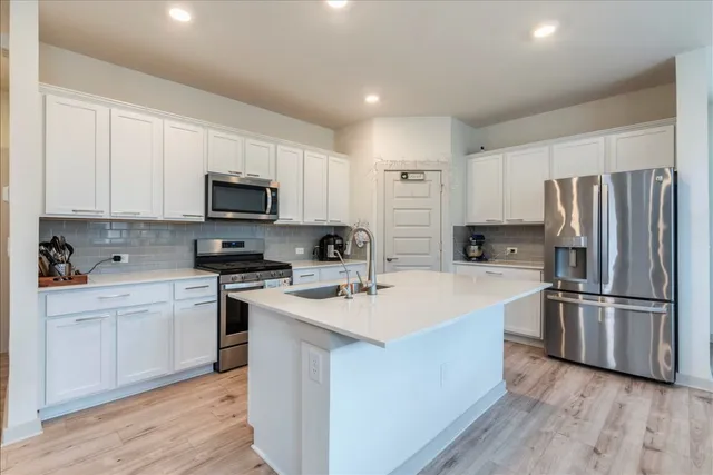 a kitchen with a sink stainless steel appliances and white cabinets