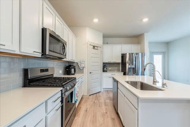 a kitchen with kitchen island granite countertop a sink and steel appliances