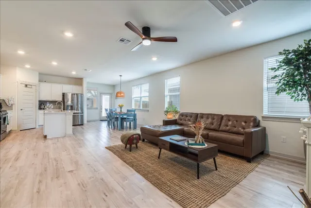 a living room with furniture and kitchen view with wooden floor