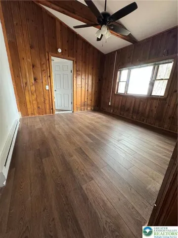 a view of an empty room with a window and wooden floor