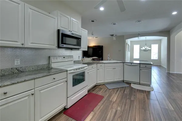 a kitchen with granite countertop a sink cabinets stainless steel appliances and wooden floor