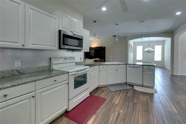 a kitchen with granite countertop a sink cabinets stainless steel appliances and wooden floor