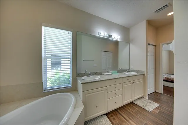 a bathroom with a granite countertop double vanity sink a mirror and a bathtub