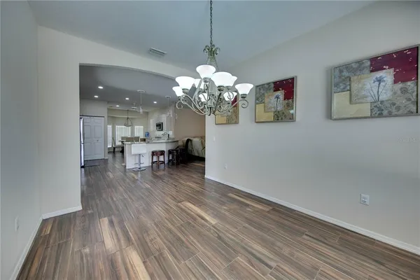 a dining room with wooden floor a chandelier a glass table and chairs