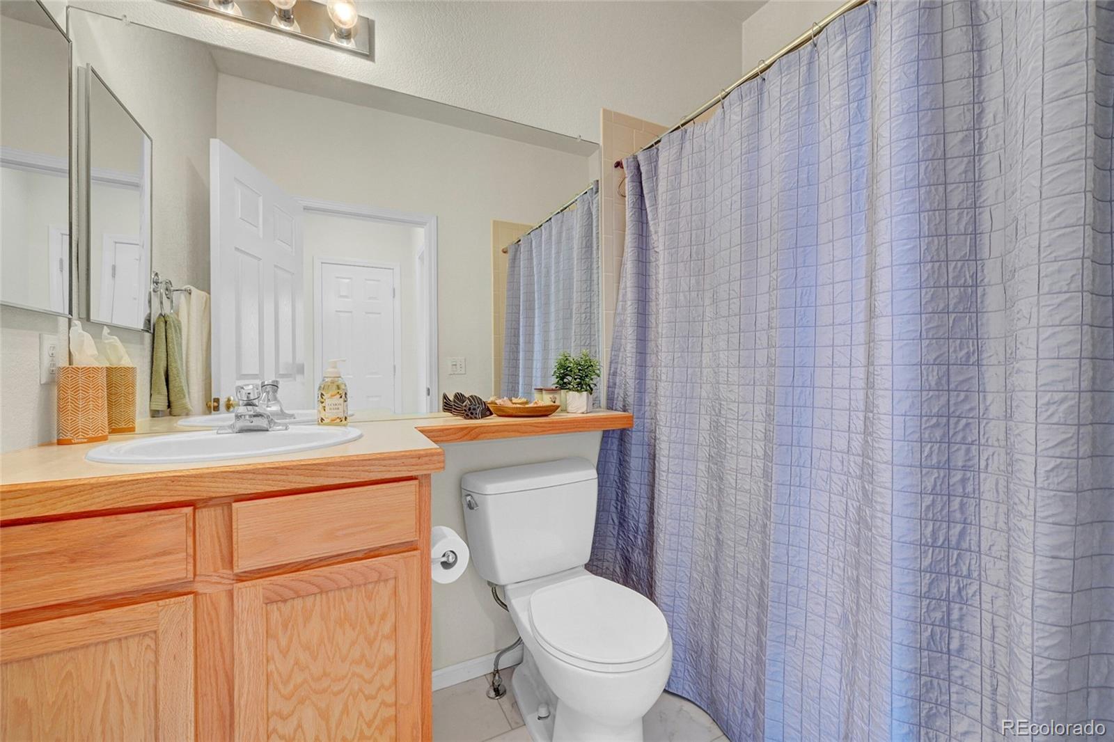 6687 South Reed Way, Unit A Littleton, CO 80123 - Photo 17 of 31 a bathroom with a granite countertop toilet a sink and a mirror