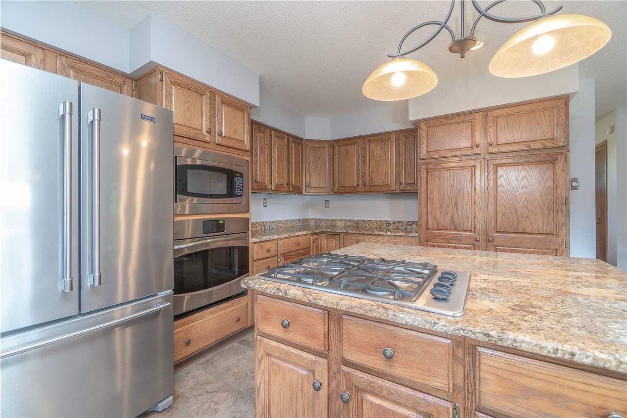 1783 West Pines Road Oregon, IL 61061 - Photo 3 of 24 a kitchen with granite countertop a refrigerator a stove a sink and dishwasher with wooden floor