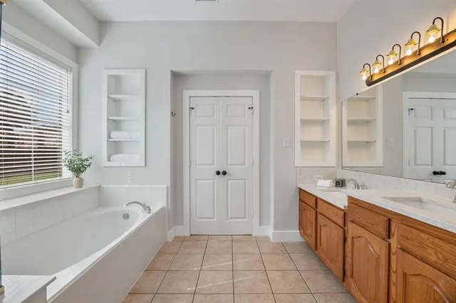 a spacious bathroom with a tub sink shower and mirror