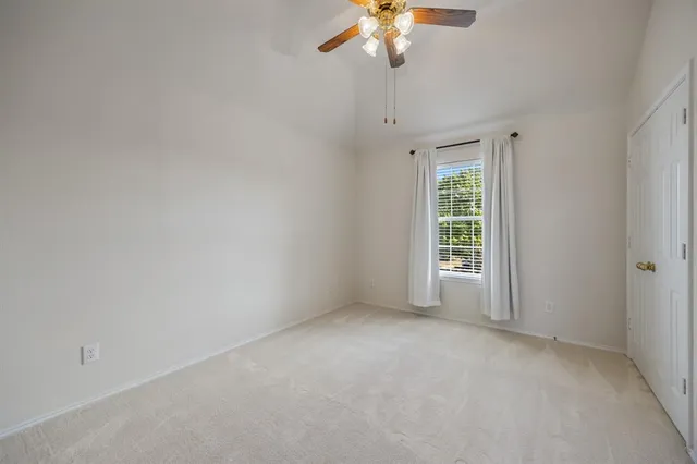an empty room with a chandelier fan and windows