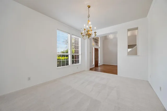 a view of an empty room with window and chandelier fan