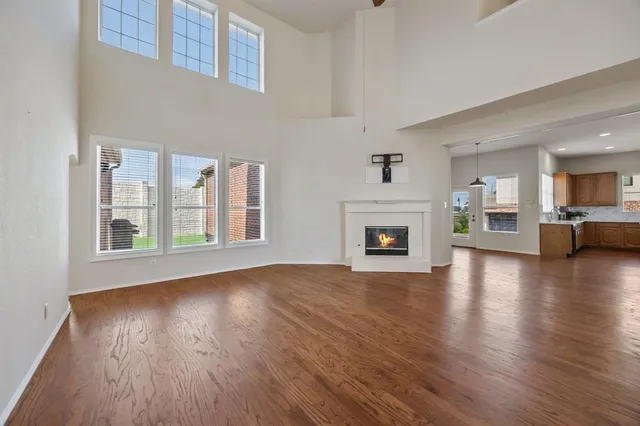 a view of an empty room with wooden floor and a fireplace