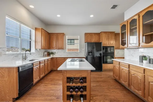 a large kitchen with stainless steel appliances granite countertop a stove a sink dishwasher and cabinets with wooden floor