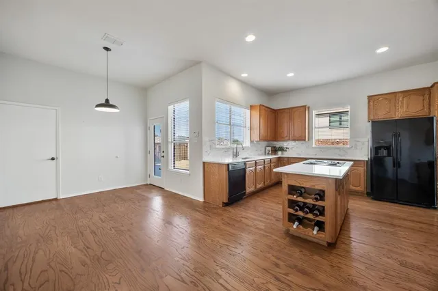 a kitchen with stainless steel appliances granite countertop a refrigerator a sink dishwasher a stove and a wooden floor