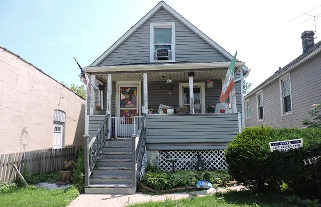 a view of small white house with a small yard and potted plants