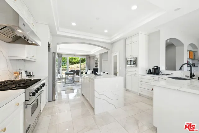 a large white kitchen with a stove a sink a dining table and chairs